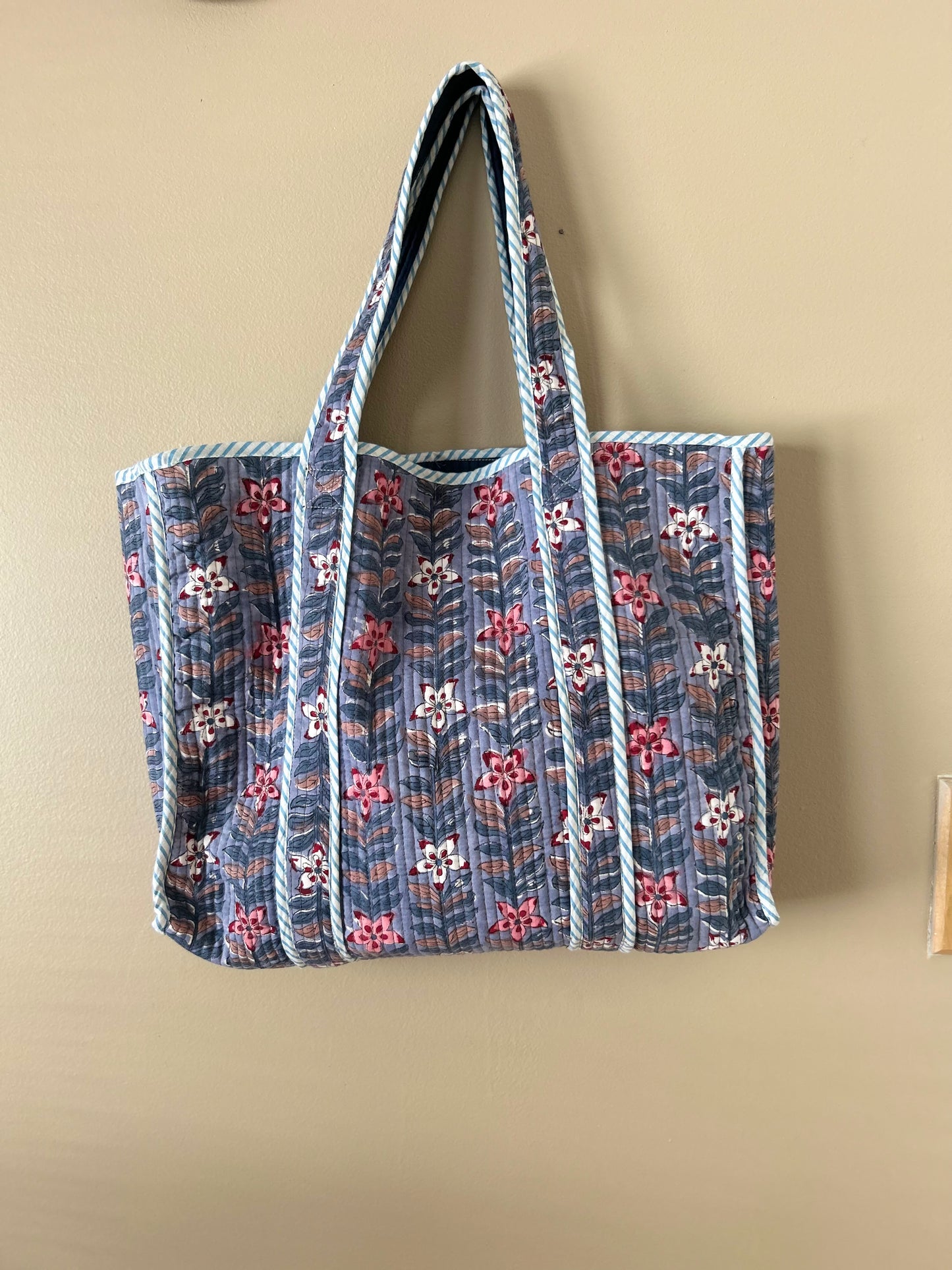 Collection of hand block printed quilted tote bags, showcasing traditional craftsmanship and contemporary designs. Available in five prints and colors: Indigo Neel, Peach Plumari, Pink Blossom, Grey Flora, and Teal Boota. Practical, spacious, and made from breathable fabrics. Support sustainable practices and empower artisans. Elevate your style with these artistic tote bags. Shop now and embrace the beauty of hand block printing.