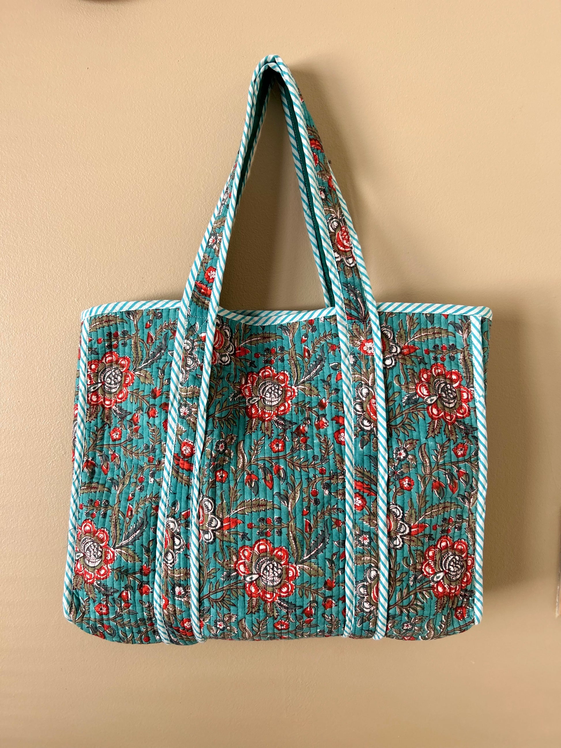 Collection of hand block printed quilted tote bags, showcasing traditional craftsmanship and contemporary designs. Available in five prints and colors: Indigo Neel, Peach Plumari, Pink Blossom, Grey Flora, and Teal Boota. Practical, spacious, and made from breathable fabrics. Support sustainable practices and empower artisans. Elevate your style with these artistic tote bags. Shop now and embrace the beauty of hand block printing.